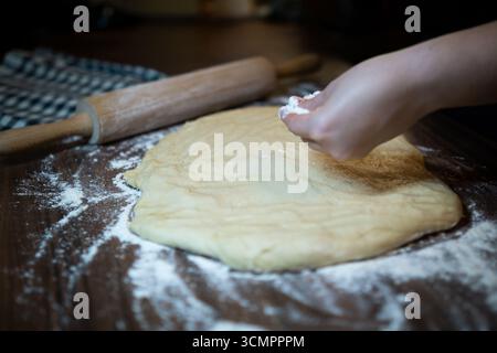 Bäcker, der Teig auf dem Küchentisch zubereitet. Hausgemachter Backprozess. Stockfoto