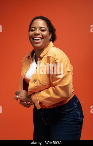Eine besonders große afroamerikanische Frau zeigt ihre herbstliche Mode mit Selbstbewusstsein und Freude in einem Studio. Stockfoto