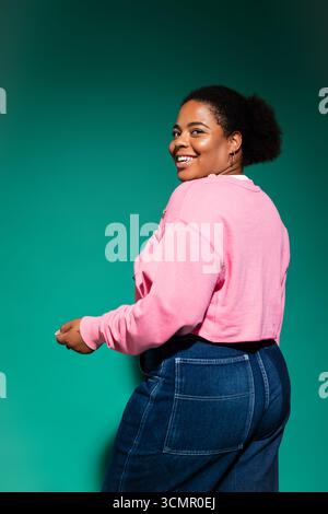 Eine selbstbewusste afroamerikanerin in Übergröße zeigt in einem Studio lebendige Herbstmode. Stockfoto