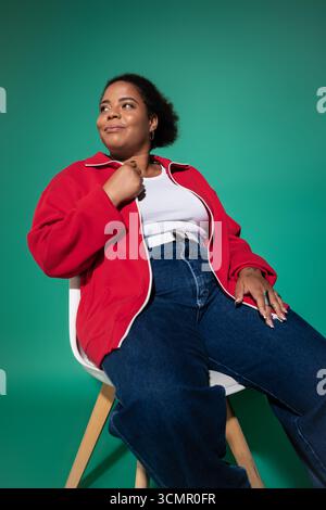 Eine selbstbewusste Schwarze Frau in Übergröße präsentiert ihr stylisches Herbstoutfit im Studio. Stockfoto