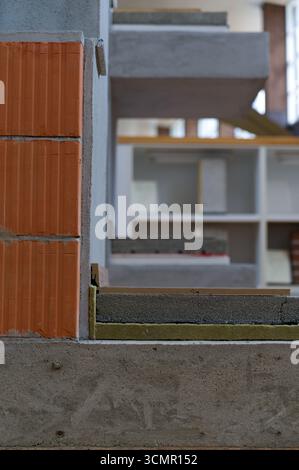 Ein Querschnitt einer Gebäudestruktur zeigt Schichten aus Ziegelstein, Beton und Dämmstoffen, die die verschiedenen Komponenten der modernen Konstruktion darstellen Stockfoto