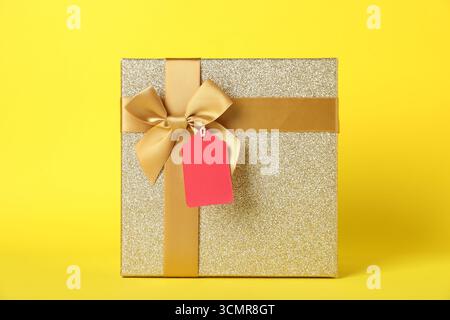Geschenkbox mit leerem Etikett auf gelbem Hintergrund Stockfoto
