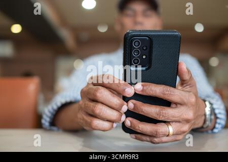 Nahaufnahme eines Reifen Mannes mit Smartphone. Junger Mann, der das Handy hält. Männliche Person, Finger und Handy-Internet für soziale Medien, E-Mail-Noten Stockfoto