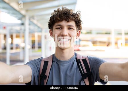 Porträt eines jungen gutaussehenden Mannes, der Selfie am Flughafenterminal mit Rucksack macht Stockfoto