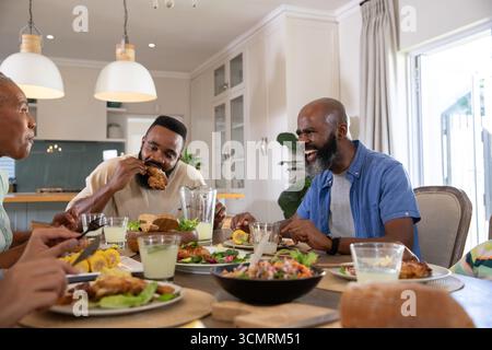 Afroamerikanische Familienessen am hölzernen Küchentisch mit gebratenem Huhn und Limonade Stockfoto