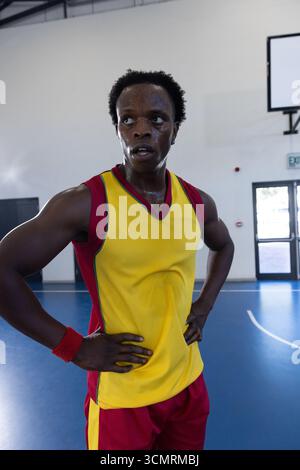 afroamerikanischer Mann, der auf blauem Platz in der Sporthalle steht und Uniform mit Anzeigetafel trägt Stockfoto