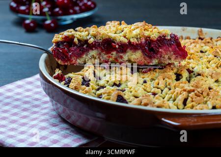 Backform mit leckerem Kirschkuchen, Nahaufnahme. Köstlicher hausgemachter Kuchen mit frischen roten Kirschen auf Holztisch. Sommer-Shortcrust-Pie mit Beeren Stockfoto