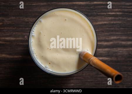 Banana Mango Smoothie mit Bambusstroh auf einem Holztisch, Nahaufnahme, Blick von oben Stockfoto