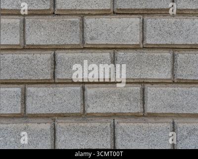 Nahaufnahme einer hellgrauen Ziegelwand mit rauer Textur und dunklen Mörtelfugen in einem verlaufenden Klebemuster, ideal für Hintergründe, Architektur und Design Stockfoto