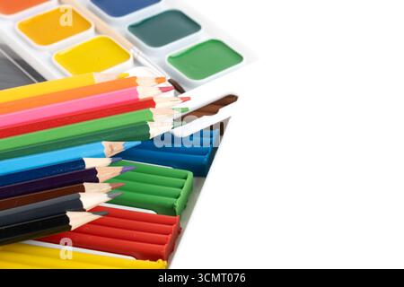 Farbige Bleistifte, Plastilin und Aquarellfarben heben sich von einem weißen Hintergrund ab Stockfoto