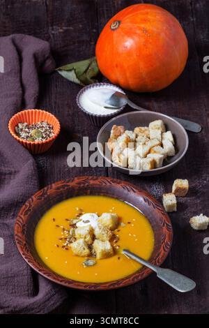 Kürbiscremesuppe serviert mit Croutons, Sahne und Samen. Stockfoto