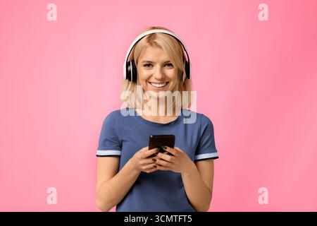 Moderne Geräte. Glückliche Frau mit schnurlosen Kopfhörern und Using Stockfoto