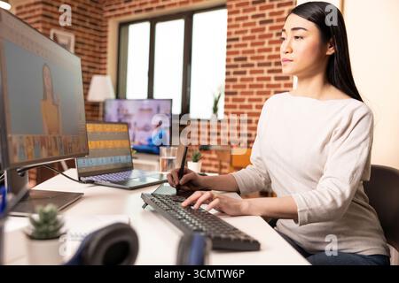 Asiatischer Grafikdesigner, der mit digitalem Zeichenblock arbeitet, Bilder retuschiert und Designelemente optimiert. Erfahrener Fotoeditor, der visuelle Details auf dem Computerbildschirm in kreativen Heimstudios perfektioniert. Stockfoto