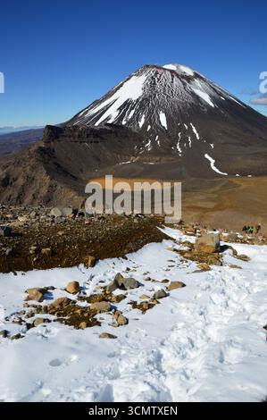 Schneebedeckter Weg auf der Tongariro Alpine Crossing mit Mount Ngauruhoe im Hintergrund, Tongariro National Park, Neuseeland, November. Stockfoto