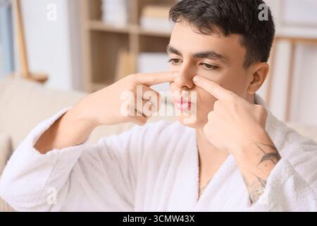 Junger Mann, der zu Hause Gesichtsaufbauübungen macht Stockfoto