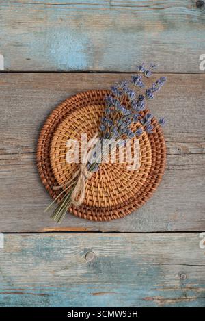 Kleiner Lavendelstrauß auf einer runden Rattan-Achterbahn auf hölzernem Hintergrund, Blick von oben Stockfoto