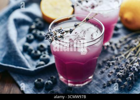 Sommerlimonade mit Lavendel, Zitronensaft und Heidelbeeren in zwei Gläsern auf dunklem Hintergrund Stockfoto