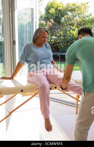Ranghohe afroamerikanerin und hispanischer Mann, der kniekontrolle auf Tisch bei Glastüren macht Stockfoto