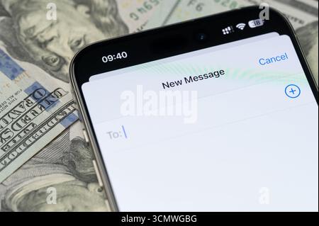 New York, USA – 12. September 2025: Erstellen Sie eine neue Nachricht in imessage auf dem Smartphone-Bildschirm mit Nahaufnahme des US-Dollar-Hintergrunds Stockfoto