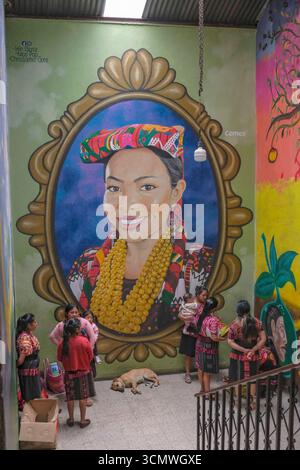Chichicastenango, Guatemala - 3. Juli 2025: Frauen neben einem Wandgemälde des Künstlers Edwin Gonzalez auf dem Santo Tomas Markt in Chichicastenango, Guatemala. Stockfoto
