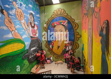 Chichicastenango, Guatemala - 3. Juli 2025: Frauen neben einem Wandgemälde des Künstlers Edwin Gonzalez auf dem Santo Tomas Markt in Chichicastenango, Guatemala. Stockfoto