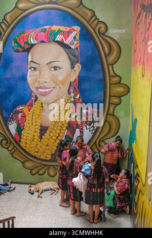Chichicastenango, Guatemala - 3. Juli 2025: Frauen neben einem Wandgemälde des Künstlers Edwin Gonzalez auf dem Santo Tomas Markt in Chichicastenango, Guatemala. Stockfoto