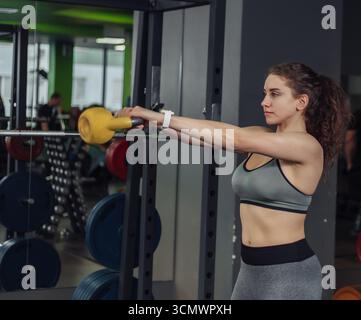 Sportliche junge fitte Frau beim Training mit Kettlebell im Fitnessstudio. Freie Gewichte, Funktionstraining Stockfoto