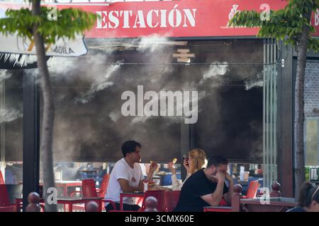 Madrid, Spanien. September 2025. Kunden essen in der Nähe eines Kühlgeräts in Madrid, Spanien, am 17. September 2025. Die spanische staatliche Meteorologische Agentur (AEMET) sagte, dass es bis September in den meisten Gebieten heißer sein wird als sonst, da die Temperaturen in einigen südlichen Gebieten voraussichtlich über 38 Grad Celsius liegen werden. Gustavo Valiente/Xinhua/Alamy Live News Stockfoto