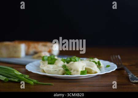 Hausgemachte Teigtaschen mit Kartoffelfüllung und frischen Kräutern. Stockfoto