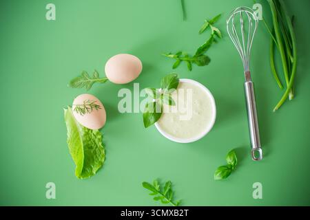 Cremige Mayonnaise aus Eiern und Kräutern in einer Schüssel mit einem Schneebesen. Stockfoto