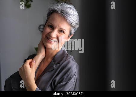 Reife schöne und gepflegte Frau während der Wechseljahre mit grauem Haar posiert. Stockfoto