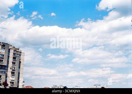 Fragment eines Gebäudes am Himmel, aufgenommen auf analogem Film. Minimalistische urbane Komposition mit sanften Tönen und körniger Textur. Stockfoto