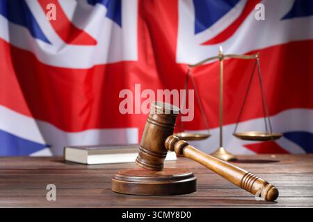 Hammer, Buch und Waage auf Holztisch vor der Flagge Großbritanniens, Großaufnahme Stockfoto