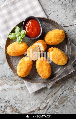 Spanische Croquettes Hühnchen in einer cremigen Bechamelsauce serviert mit Tomatensoße in Nahaufnahme auf einem Teller auf dem Tisch. Vertikale Draufsicht von oben Stockfoto