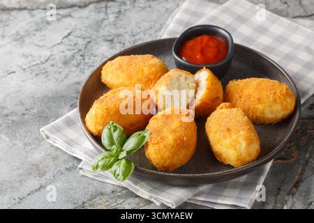 Köstliche knusprige panierte Hähnchenkroketten, serviert mit Tomatensauce in Nahaufnahme auf einem Teller auf dem Tisch. Horizontal Stockfoto