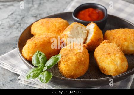 Panierte und frittierte Hähnchenkroketten serviert Tomatensauce in Nahaufnahme auf einem Teller auf dem Tisch. Horizontal Stockfoto