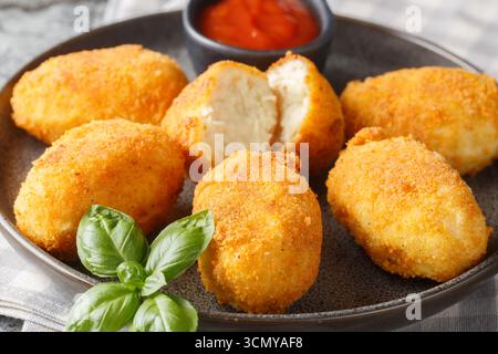 Spanische Croquettes Hühnchen in einer cremigen Bechamelsauce serviert mit Tomatensoße in Nahaufnahme auf einem Teller auf dem Tisch. Horizontal Stockfoto