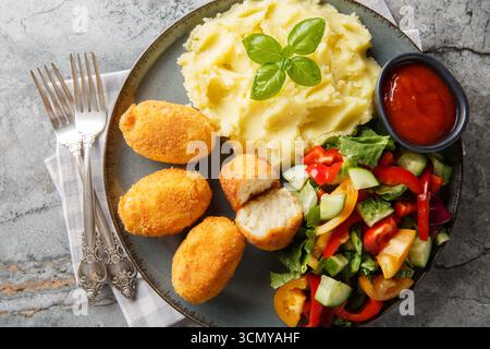 Spanische Croquettes Hühnchen in einer cremigen Bechamelsauce serviert mit Kartoffelpüree, frischem Salat und Tomatensauce in Nahaufnahme auf einem Teller auf dem Tisch. Hori Stockfoto