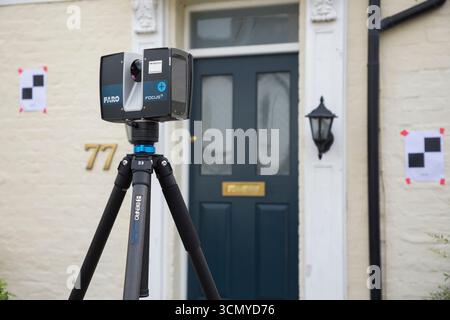Ein Laserscanner auf einem Stativ, der während einer Vermessung für eine Planungsanwendung in einem Wohnhaus/Gebäude verwendet wird. Ziele sind an der Wand. UK. (140) Stockfoto