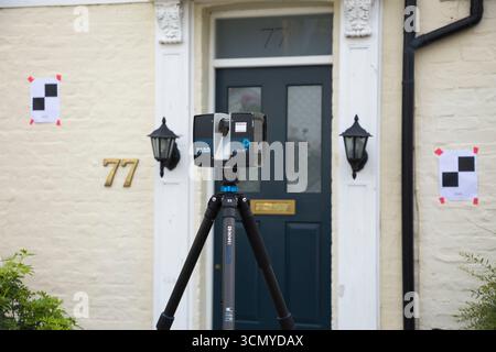Ein Laserscanner auf einem Stativ, der während einer Vermessung für eine Planungsanwendung in einem Wohnhaus/Gebäude verwendet wird. Ziele sind an der Wand. UK. (140) Stockfoto
