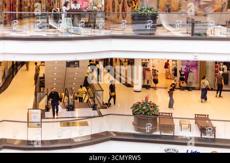 Berlin, Deutschland - 1. September 2025: An einem sonnigen Nachmittag ziehen Menschenmassen durch ein modernes Einkaufszentrum in Berlin. Die Leute fahren auf Rolltreppen und fahren Stockfoto
