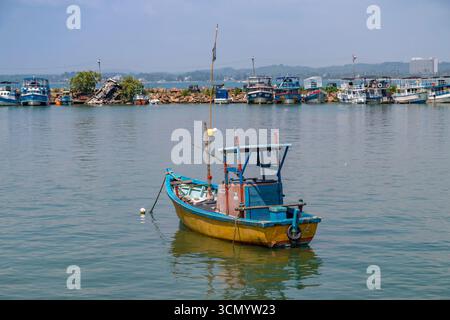 Sri Lanka - Weligama - Gelbes Fischerboot - Einzelboot schwimmt auf ruhigen Gewässern Stockfoto