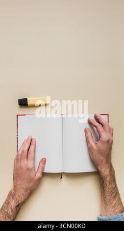 Top-down-Ansicht eines Mannes, der Notizen in einem Bullet Journal macht. Kreatives Schreiben, Planen und Leere-Page-Syndrom auf einem isolierten Modell. POV isoliert. Stockfoto