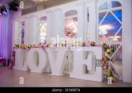 Ein atemberaubender Veranstaltungsort für Hochzeiten bietet große weiße Buchstaben mit der Schreibweise „LIEBE“, die mit bunten Blumen verziert sind. Die wunderschöne Kulisse sorgt für eine romantische Atmosphäre Stockfoto
