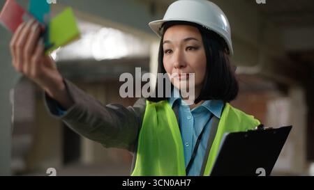 Asiatische koreanische Designerin Frau, die Farbe Reparatur weibliche Entwicklerin Architekt professioneller Ingenieur Baumeister Gebäudeplanung Haus Renovierung Design wählt Stockfoto