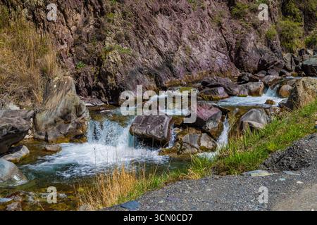 Ein ruhiger Fluss fließt sanft über glatte Felsen in einer bergigen Region in Kirgisistan am sonnigen Frühlingstag. Stockfoto