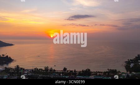 Ein atemberaubender Blick aus der Luft auf den Kata Beach in Phuket, Thailand, während des Sonnenuntergangs. Das Bild zeigt die Küste, kleine Inseln und üppig grüne hil Stockfoto