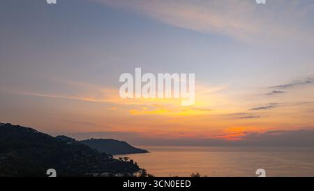 Ein atemberaubender Blick aus der Luft auf den Kata Beach in Phuket, Thailand, während des Sonnenuntergangs. Das Bild zeigt die Küste, kleine Inseln und üppig grüne hil Stockfoto