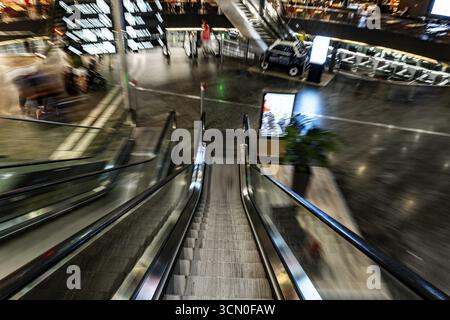Beleuchteter Flughafen Zürich mit Eskalator in unscharfer Bewegung bei Nacht im Flughafen Kloten, Zürich, Kanton Zürich, Schweiz Stockfoto