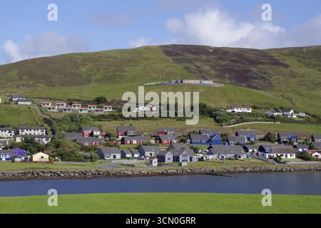 Ein malerisches Dorf mit farbenfrohen Häusern an der Küste und grünen Hügeln, Scalloway, Shetland Islands, Schottland, Großbritannien Stockfoto